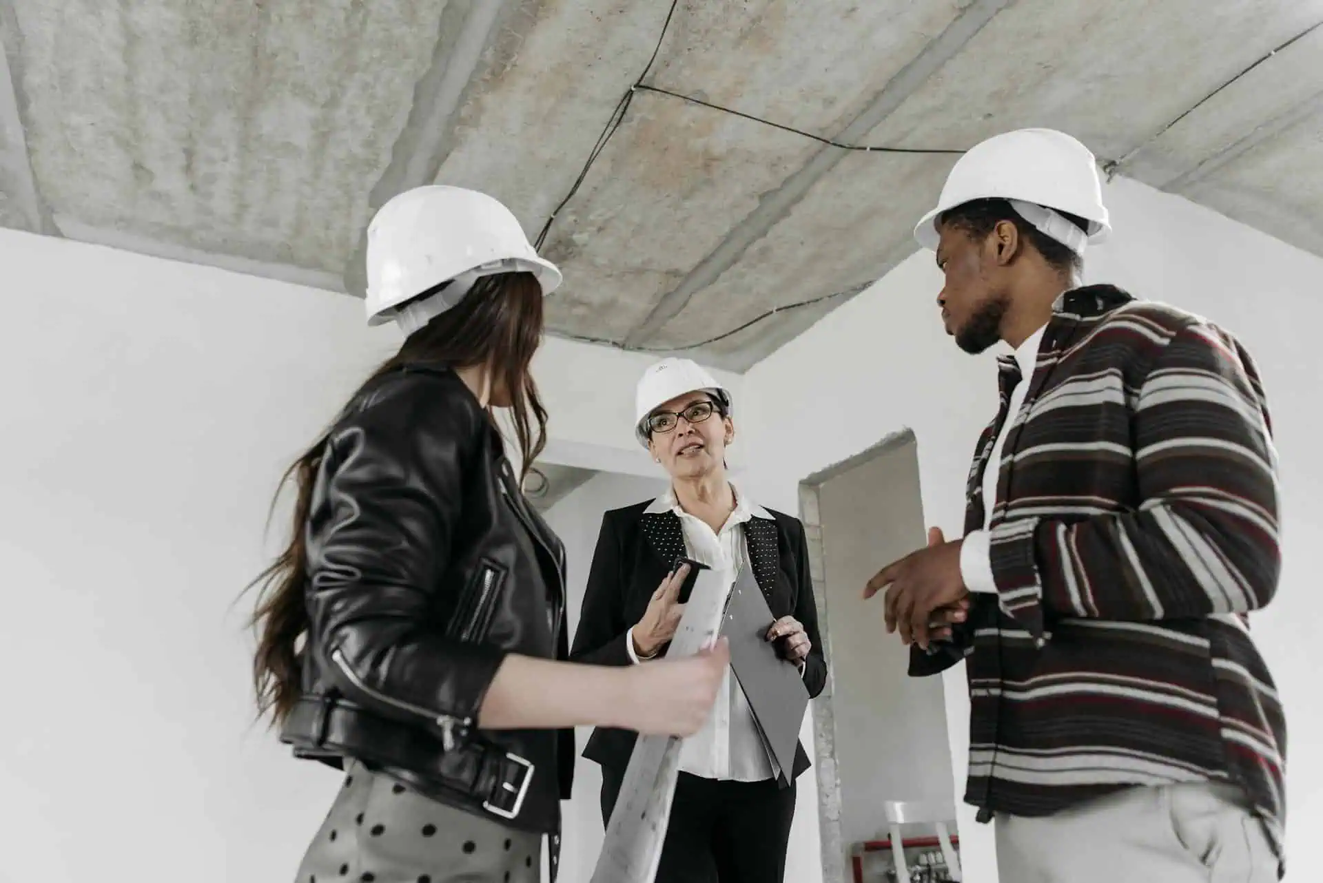 Construction team in hard hats reviewing progress inside an unfinished building.